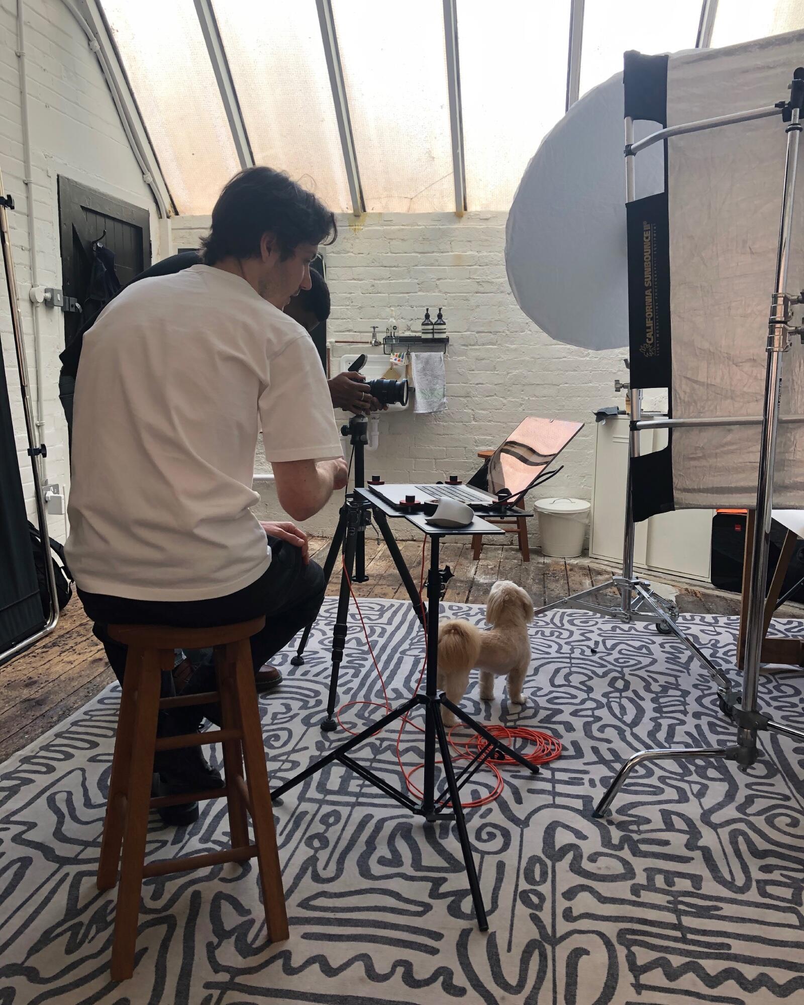 Behind the scenes of the Fetchamo Core Backpack studio photoshoot, showing the photographer's setup, lighting and Shih Tzu on set.