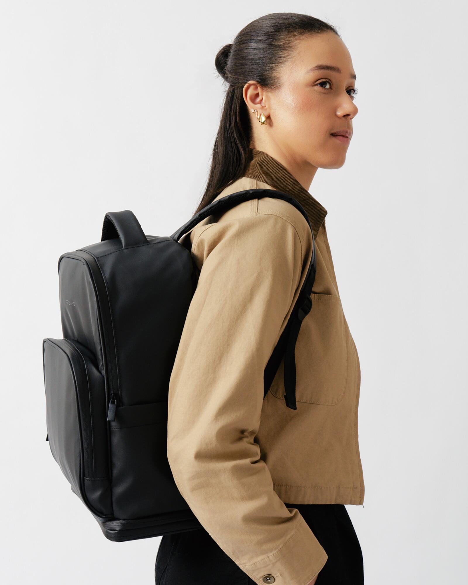 Model wearing the Fetchamo Core Backpack during a minimalist studio campaign photoshoot.