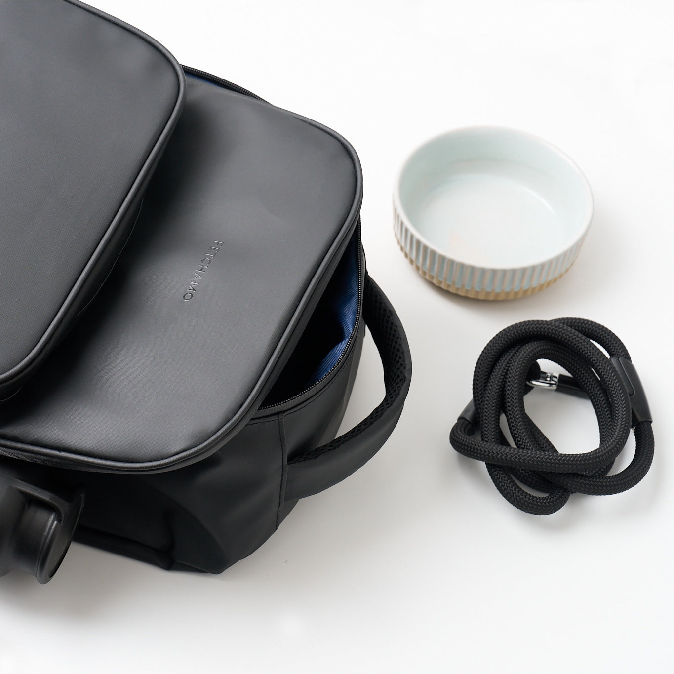 Black Fetchamo Core Backpack with the top compartment open, revealing the dark blue interior lining, alongside a dog bowl and lead.